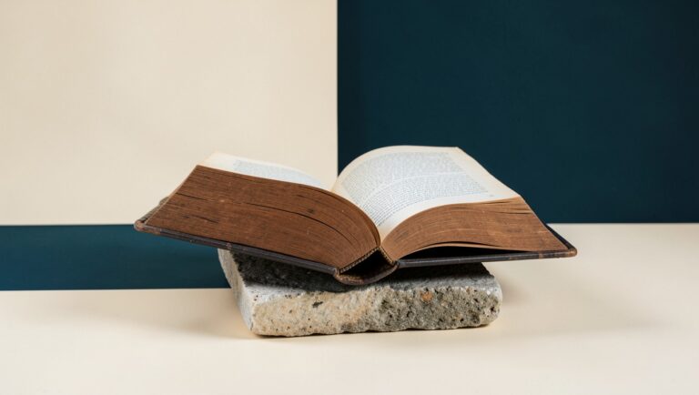 A heavy wooden reference book open on a stone reading stand.